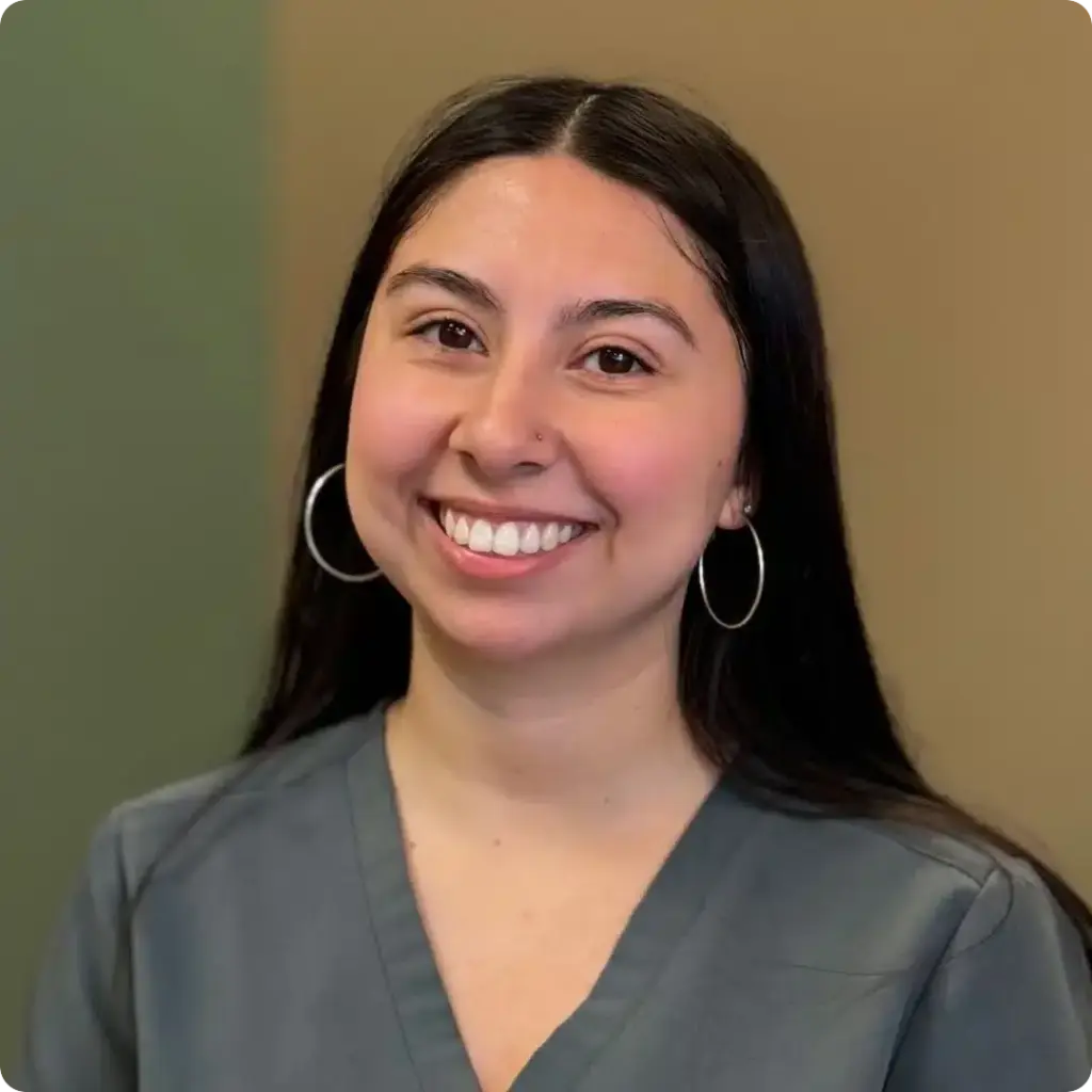 Alexa, Orthodontic Assistant, smiling in scrubs with hoop earrings in a professional portrait at Beaverton Orthodontics in Beaverton, OR